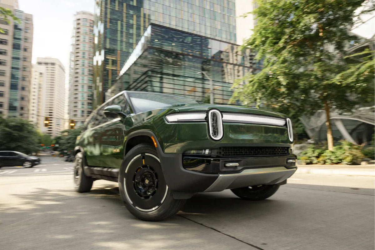 Green Rivian R1S driving along a city street